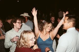 People dancing and celebrating at a lively nighttime party with raised arms and drinks in hand.