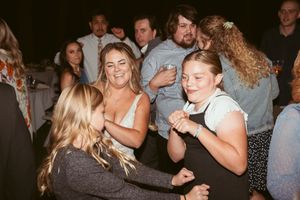 Party goers enjoying themselves and dancing energetically on a dimly lit dance floor at a nighttime celebration.