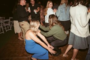 Candid shot of guests dancing and crouching on a dance floor at an evening event.