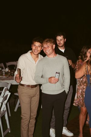 People enjoying a casual outdoor evening gathering with drinks at what appears to be a party or reception.
