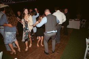 People dancing at a festive indoor event with string lights visible overhead.