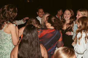 A lively crowd of people dancing together at a party in a dimly lit room with joyful energy.