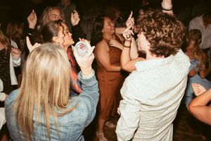 People dancing and celebrating in a large group at a nighttime social gathering or party.