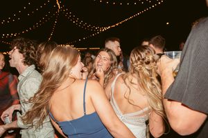People dancing under decorative string lights at a nighttime celebration.