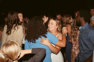 Wedding guests dancing and celebrating on the dance floor under string lights at an outdoor reception.