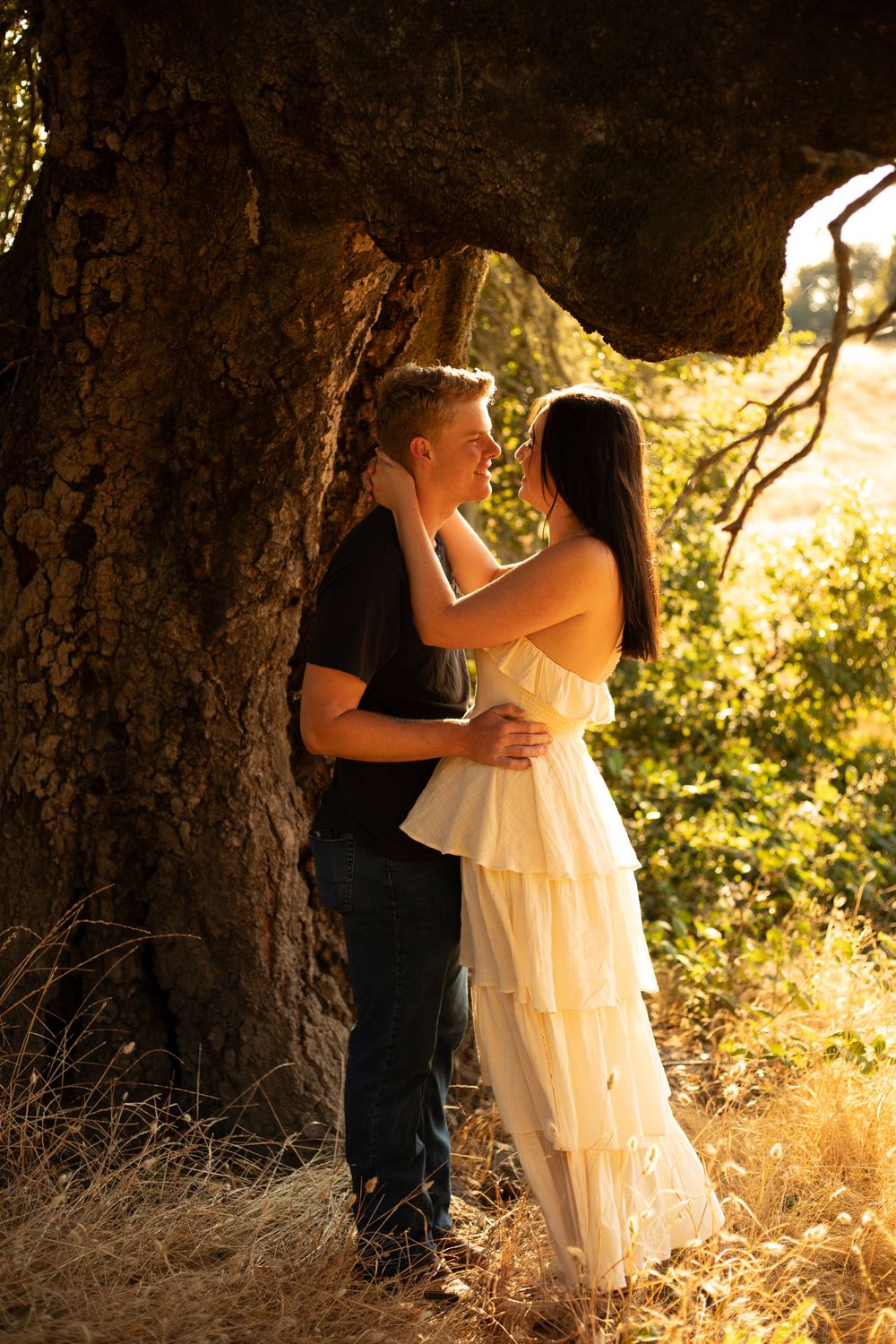 Couple sharing an intimate moment under a natural tree cave during sunset.