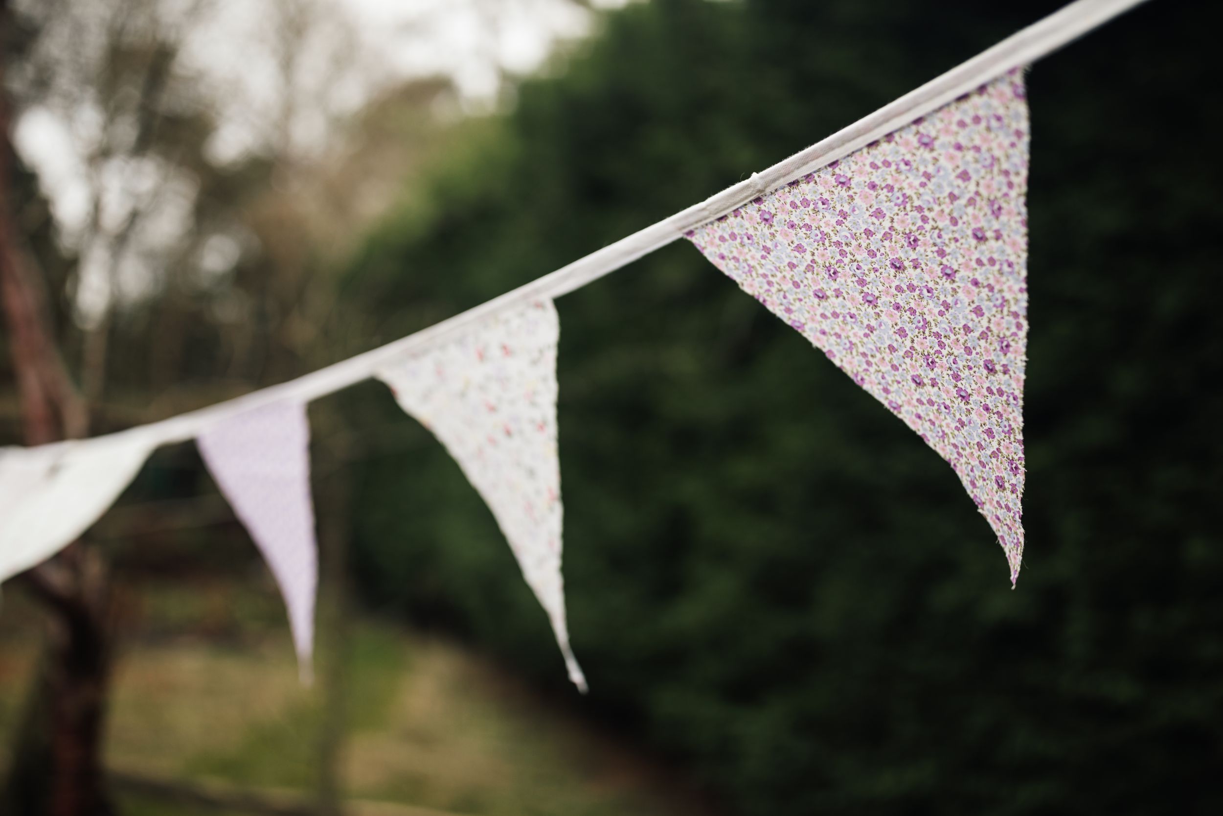 Decorative white bunting banners with polka dot patterns hang against a blurred outdoor background.