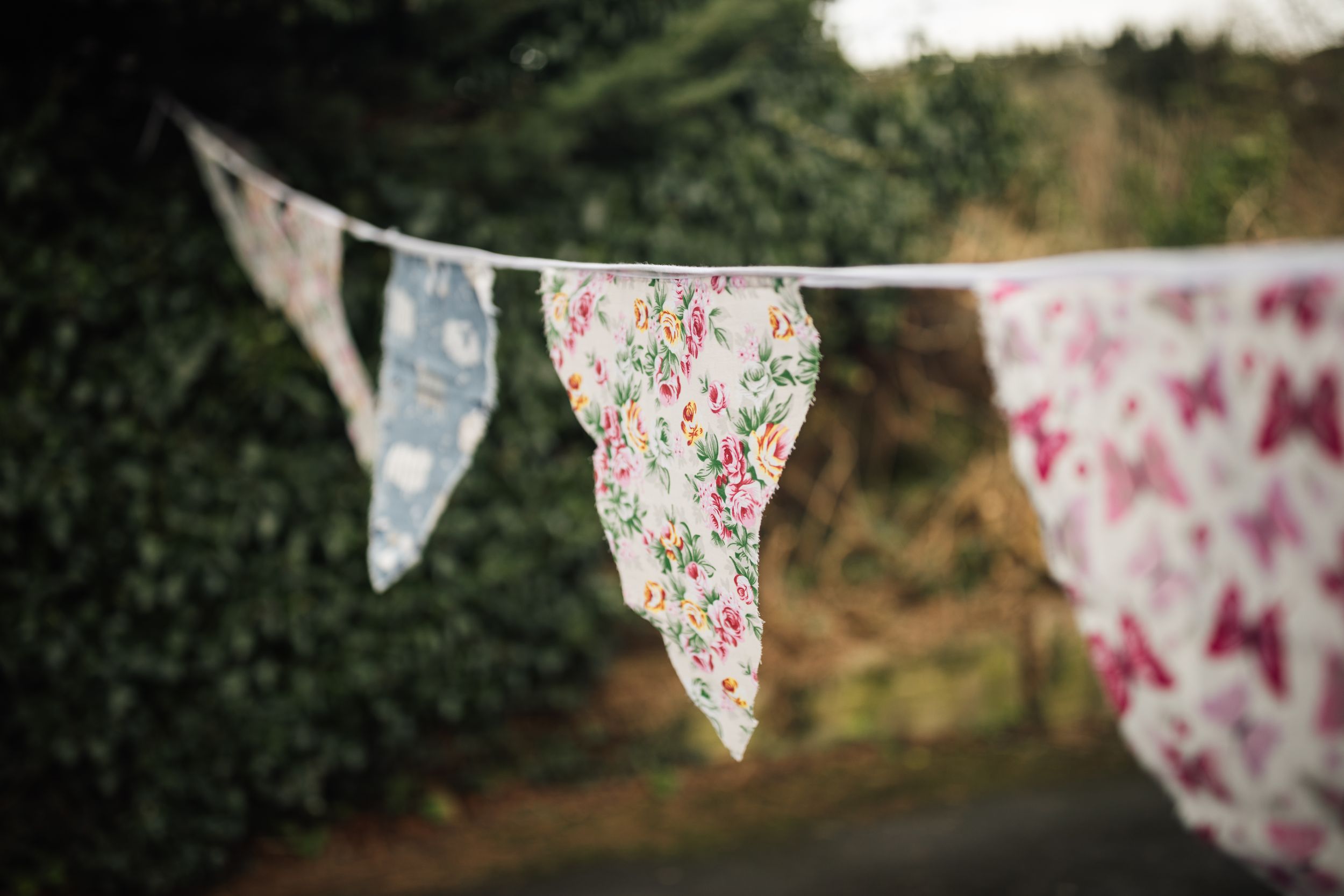 Floral and butterfly patterned bunting decorations hang across a garden setting creating a whimsical outdoor atmosphere.