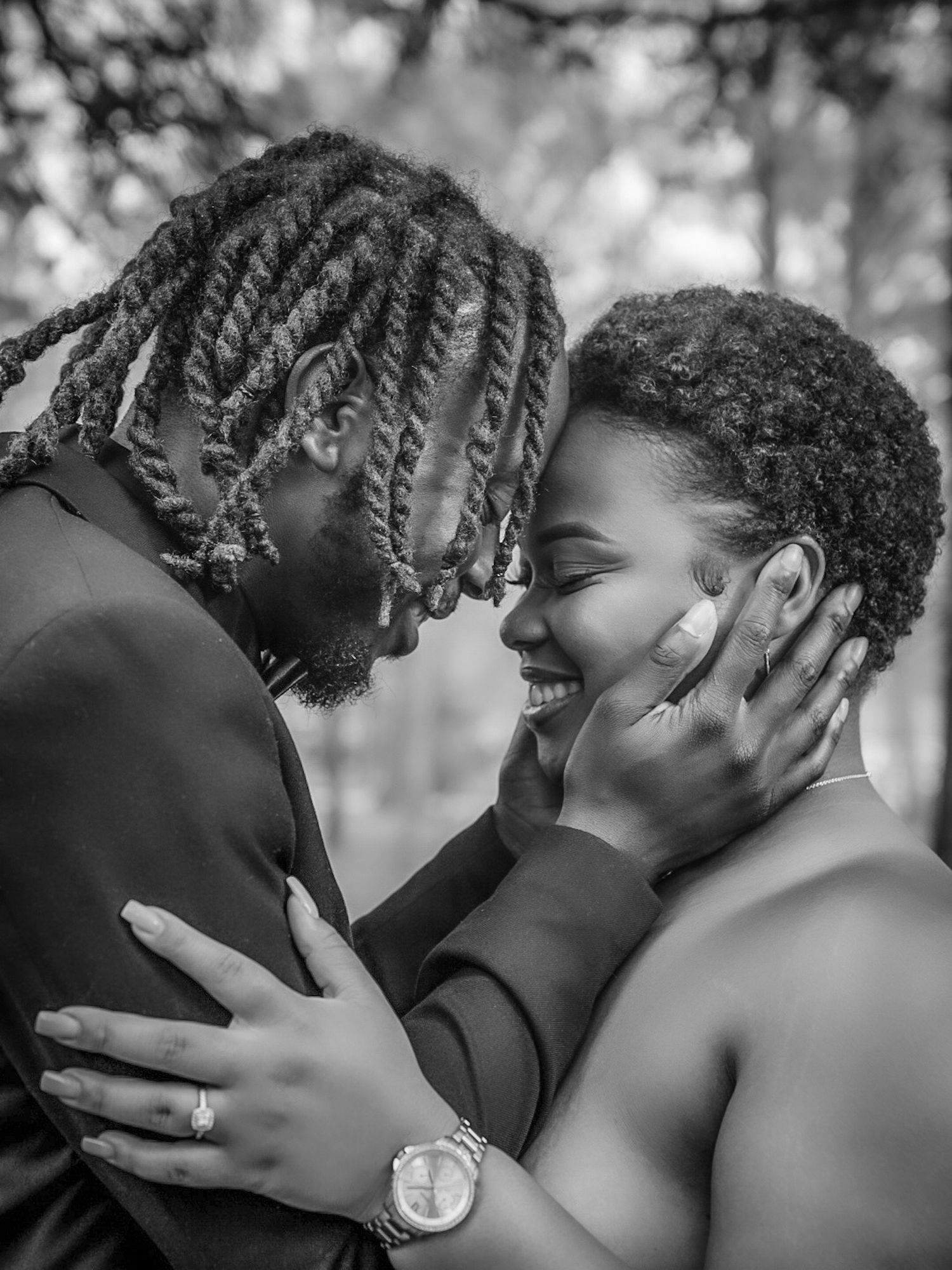 Black and white photo of couple sharing a tender moment, man cradling womans face as she smiles.
