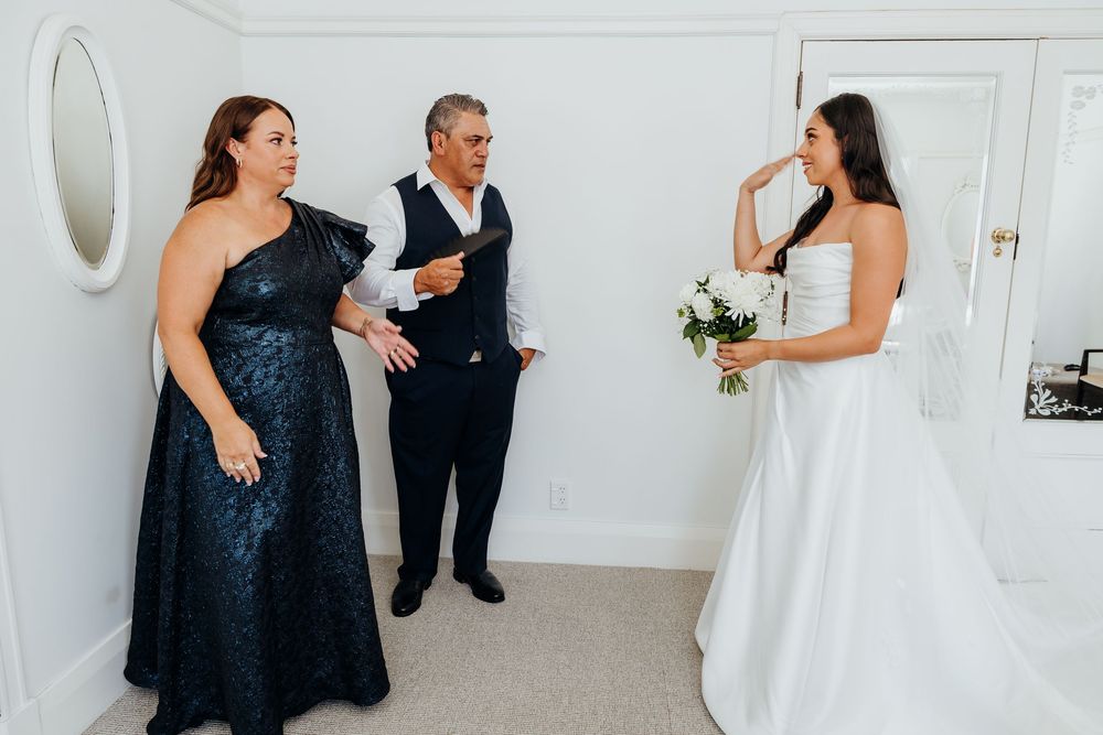 Bride in white strapless gown shares an emotional moment with her parents before the wedding ceremony.