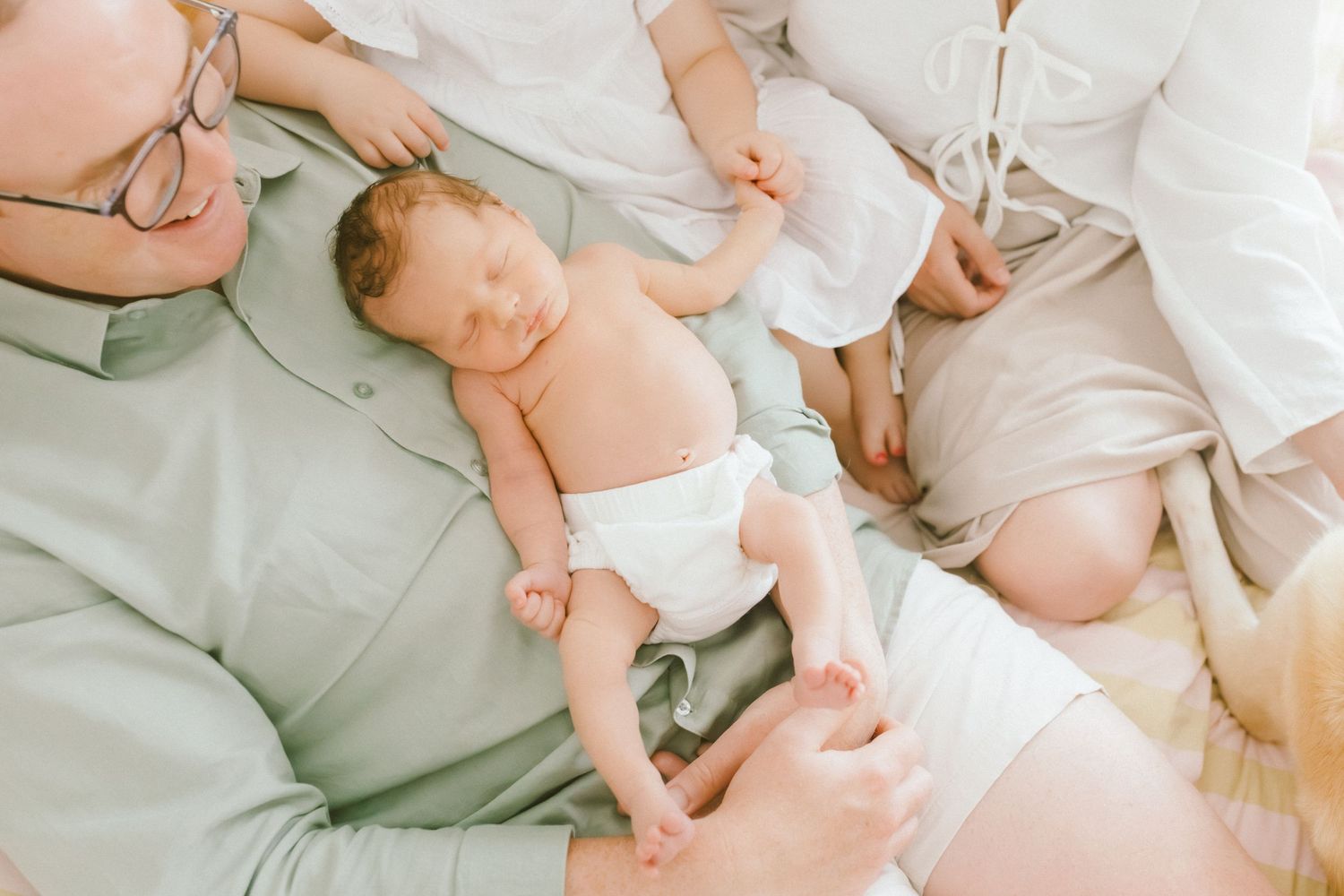 Newborn baby in diaper lying between parents during an intimate family lifestyle newborn photography session.