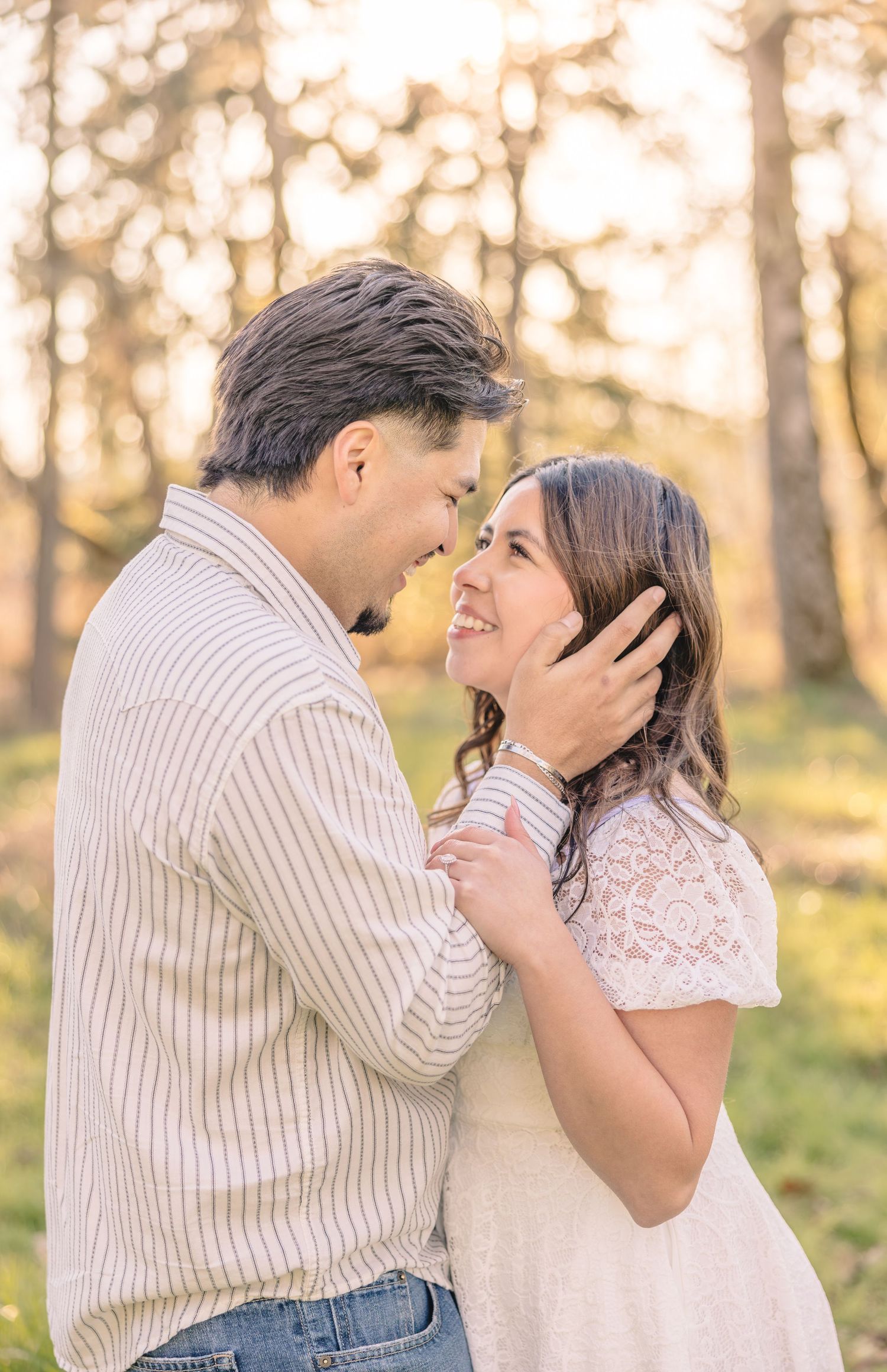 Couple sharing a romantic moment outdoors, man tenderly holding woman's face, smiling at each other in golden sunlight.