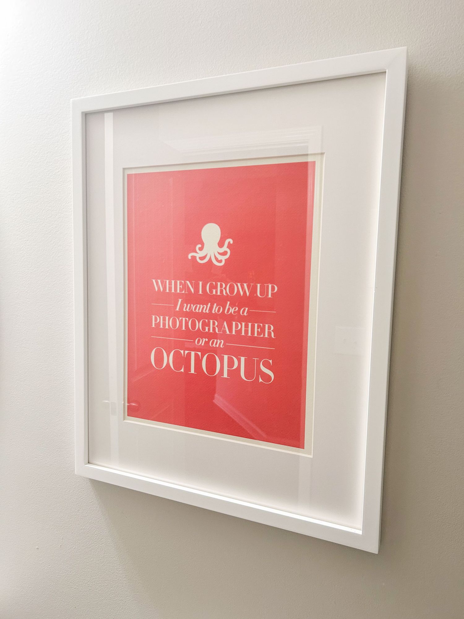 White framed coral print with octopus illustration reading When I Grow Up I Want to Be a Photographer or an Octopus.