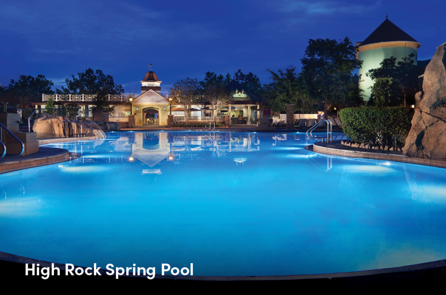 Night view of High Rock Spring Pool with blue illuminated waters and resort architecture.