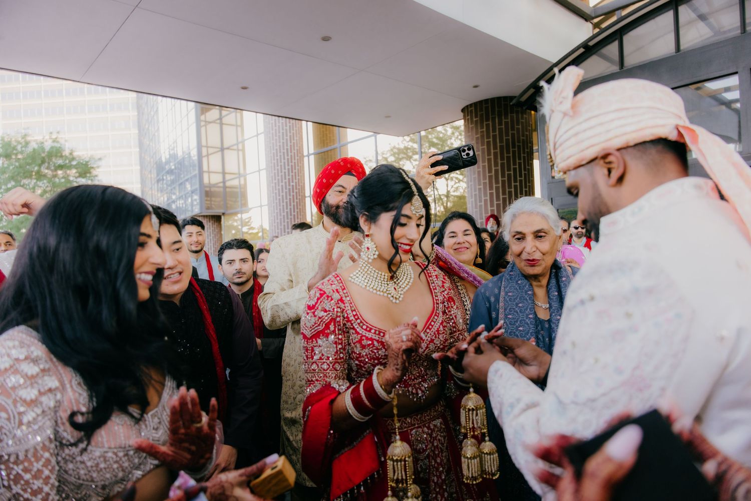 Bride in sparkling silver lehenga dancing joyfully at a dimly lit wedding reception celebration.