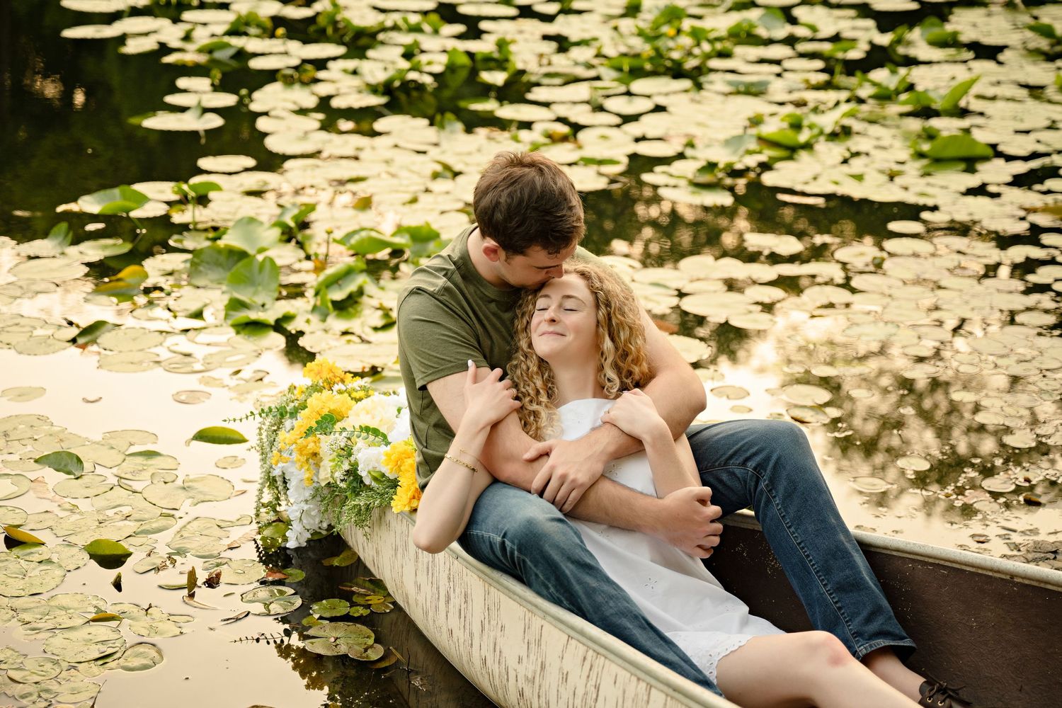 A romantic proposal scene set between rows of grapevines in a scenic vineyard with white flowers and a blanket.