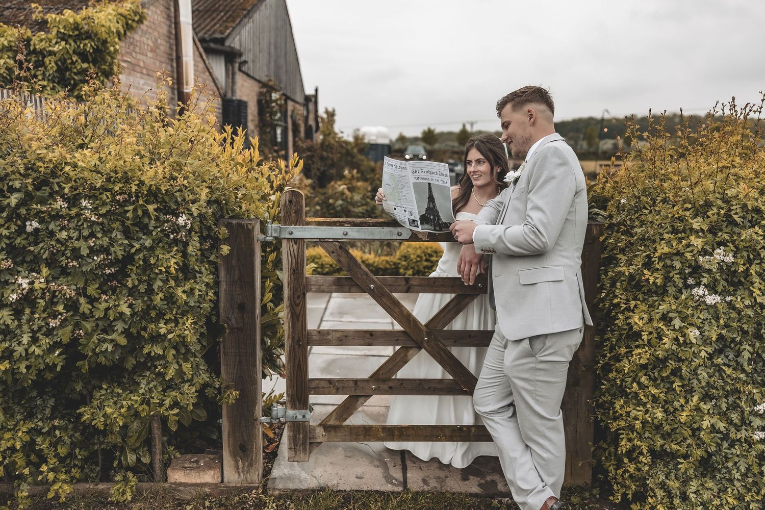 Prompted couple image reading their wedding newspaper in Beverley Barns gardens.