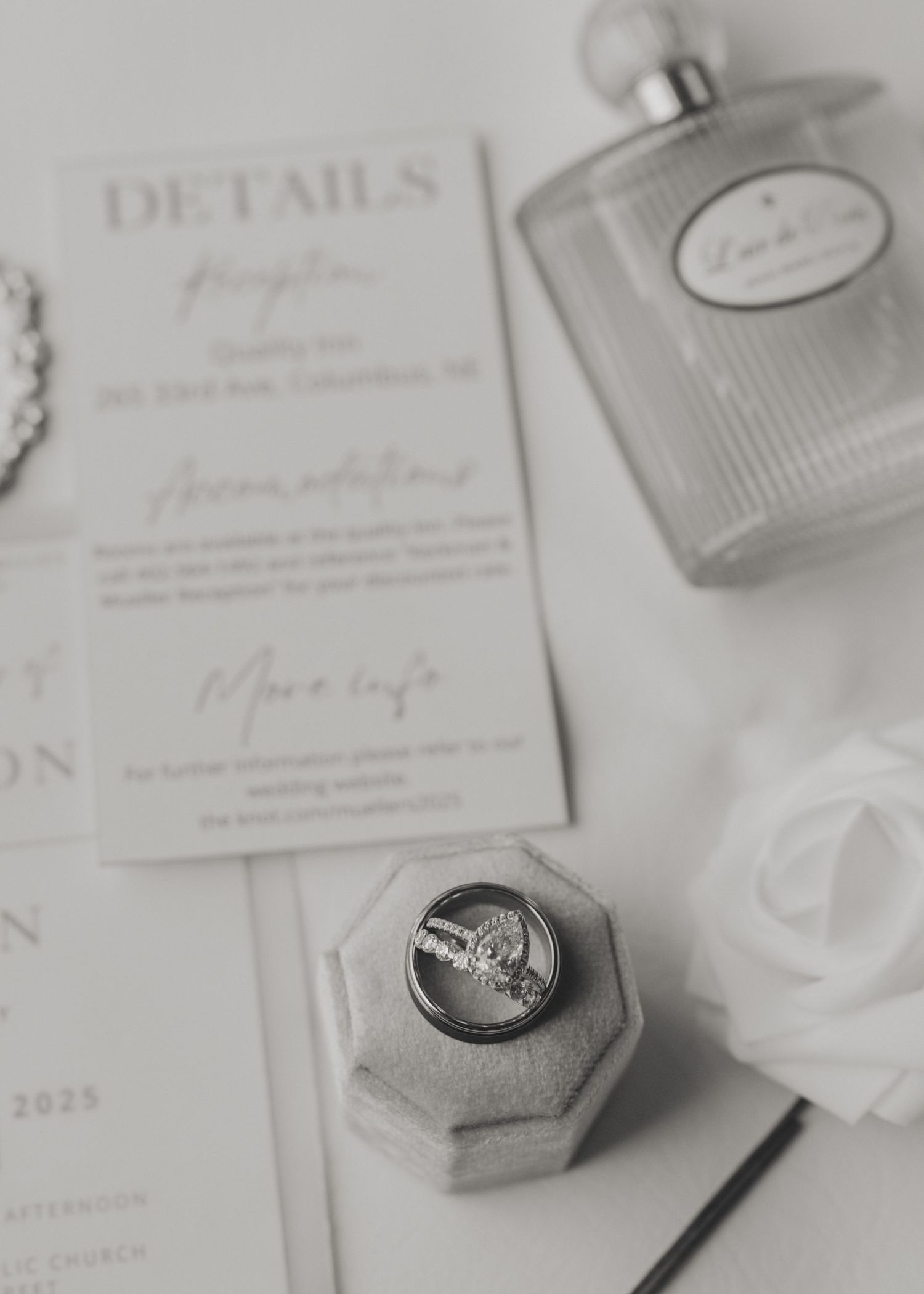 Black and white wedding stationery and ring details arranged artistically on a light surface.