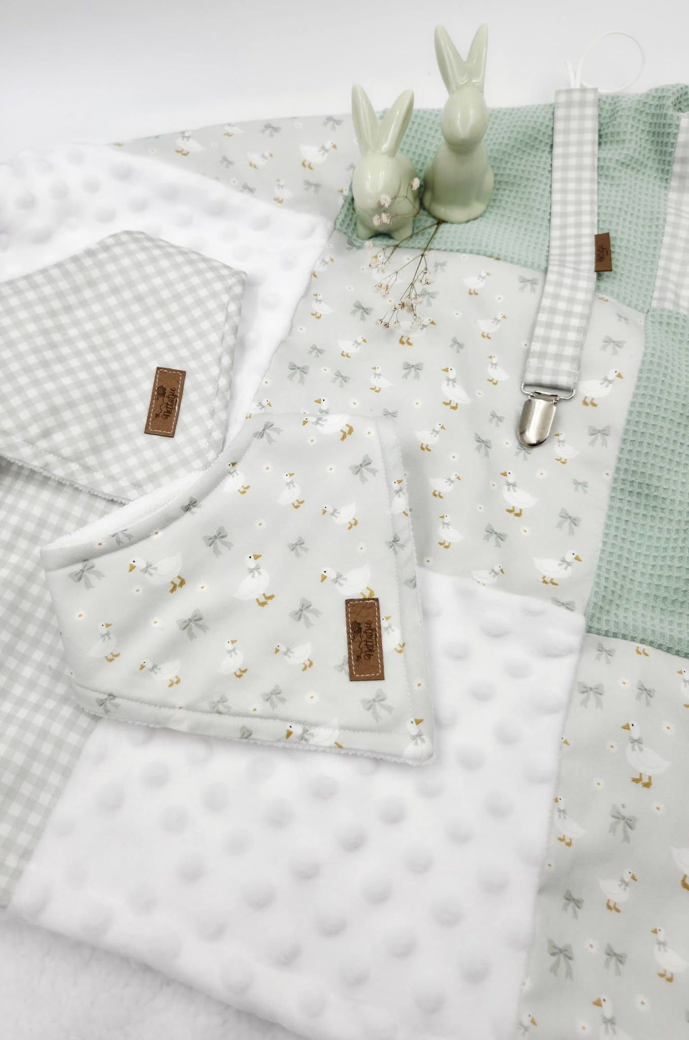 Sage green baby gift set with floral fabric, minky blanket, bib, and bunny figurine decoration.