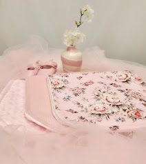 Elegant pink floral baby blanket set with rose embroidery, satin bow, and delicate white flowers in a soft pastel arrangement.
