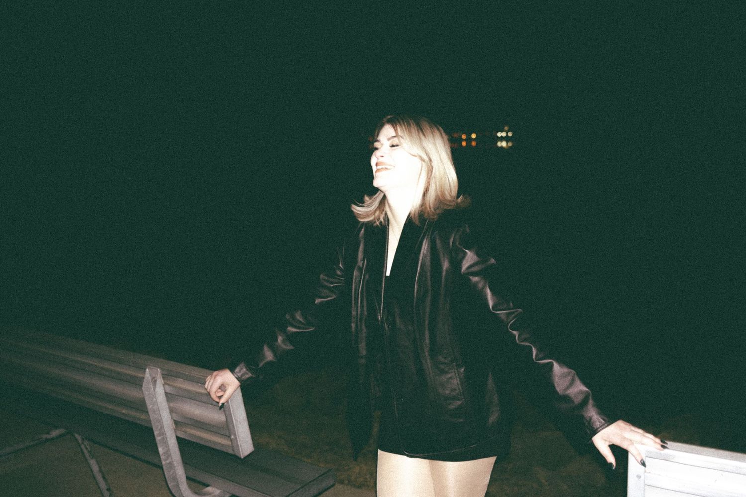 Person dancing alone on a dark empty road at night in black and white photography.