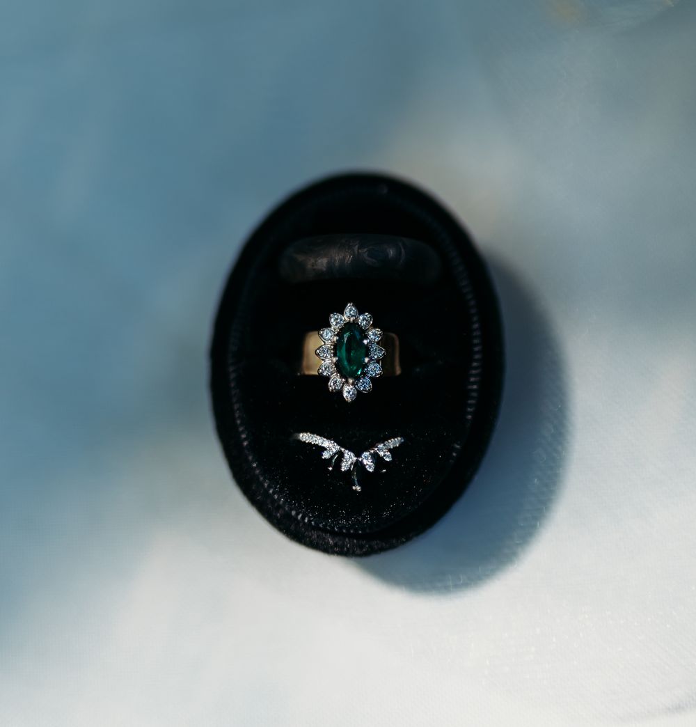 Emerald and diamond engagement ring with chevron wedding band in black ring box.