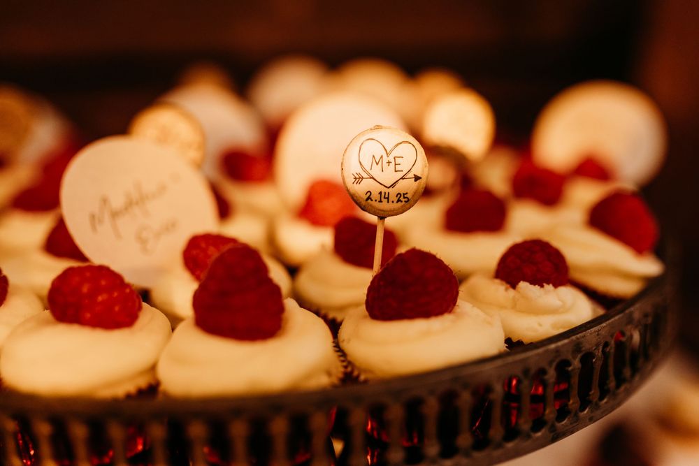 Elegant cupcakes topped with fresh raspberries and cream cheese frosting displayed on a decorative tiered stand.
