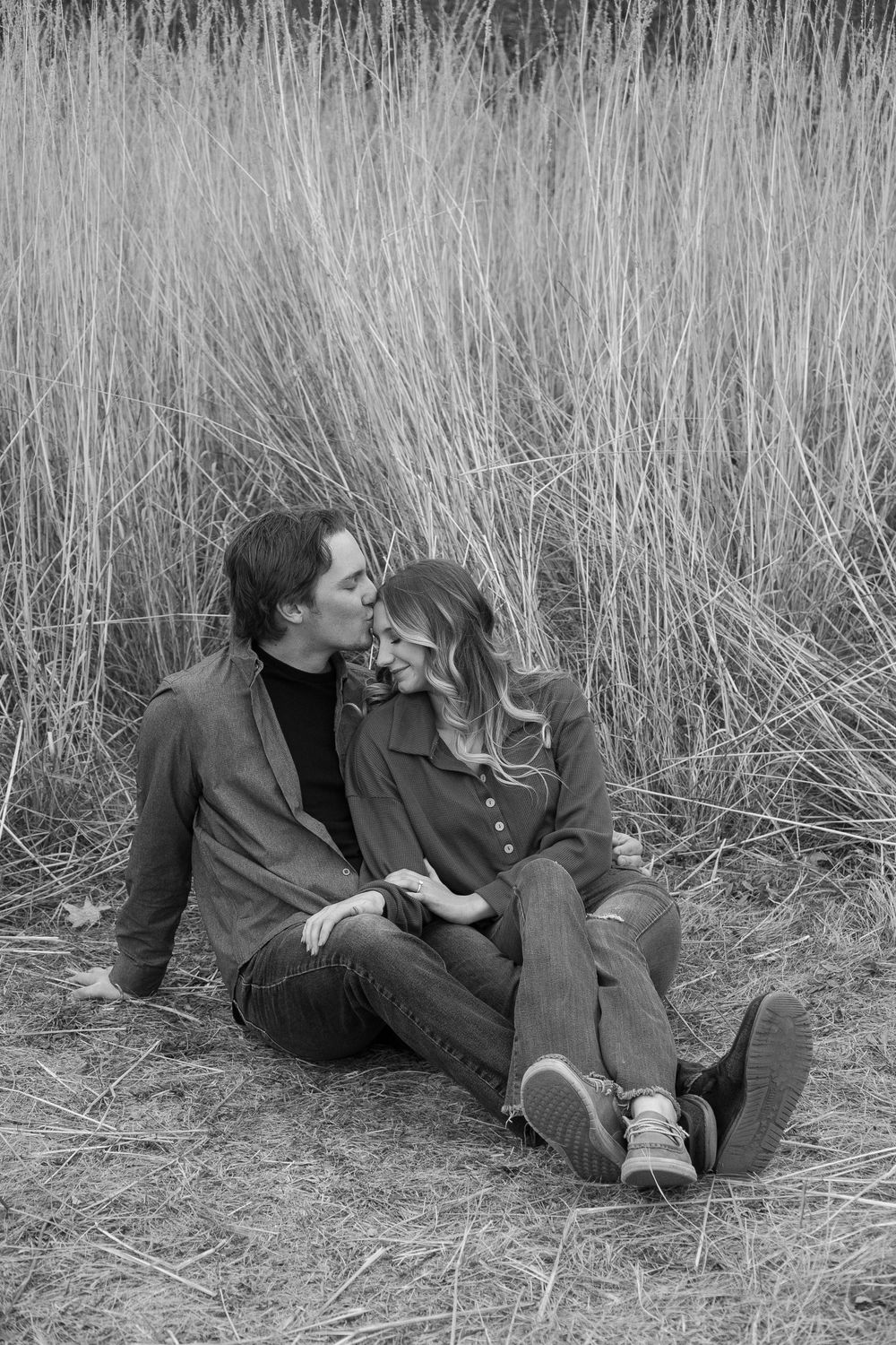 Black and white photo series showing a couple laying in tall grass sharing an intimate moment together.