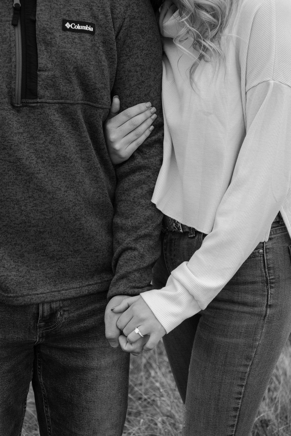 A couple in casual attire, wearing jeans and sweaters, holding hands in a series of black and white photos.