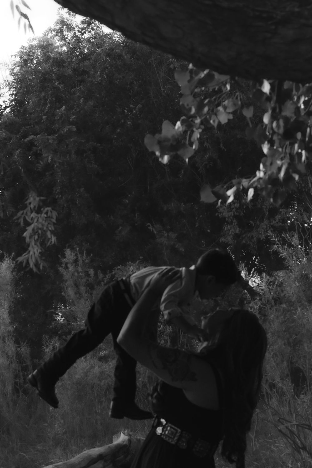 Artistic black and white photo showing silhouettes against a natural backdrop with trees.