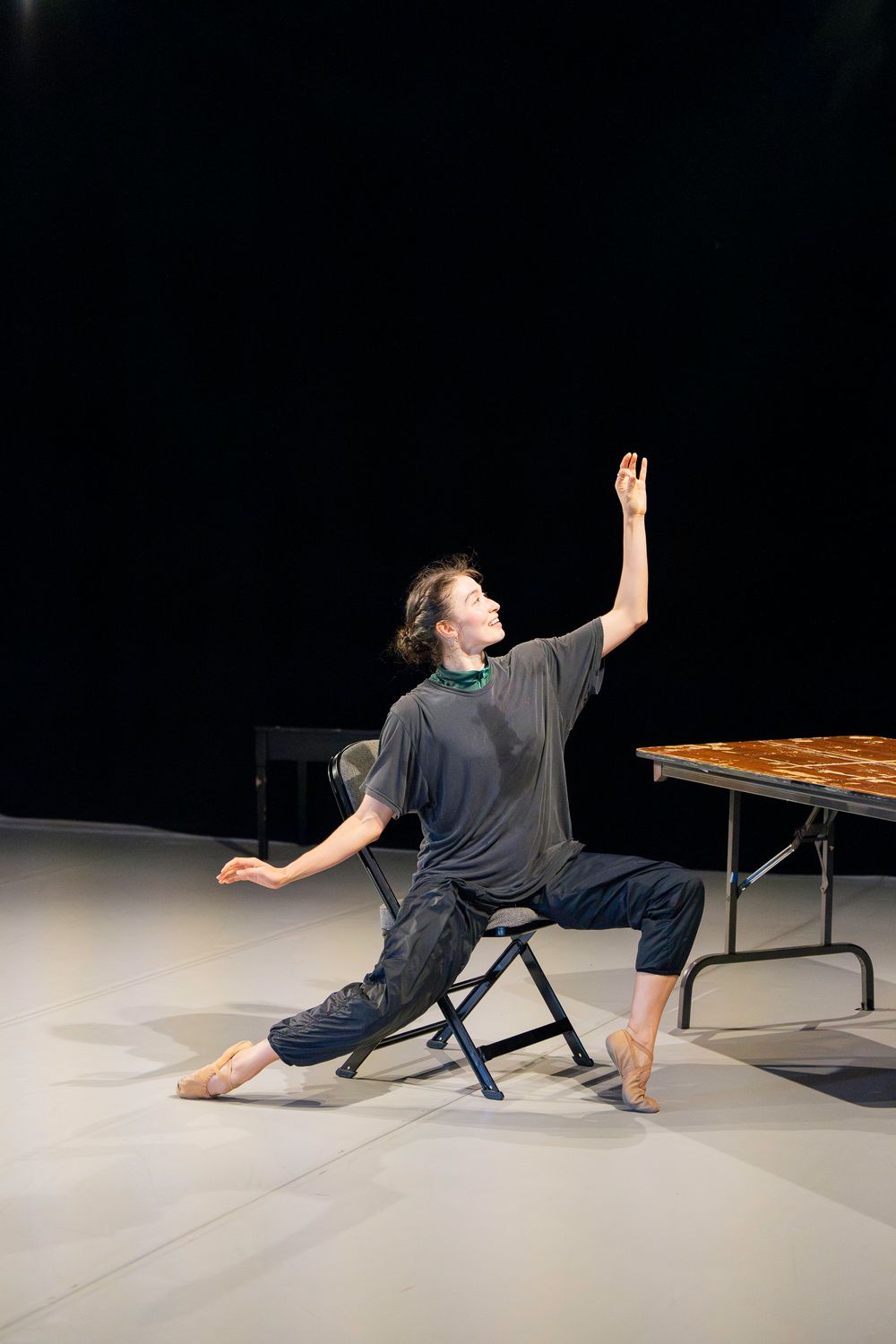 Contemporary dancer performs a fluid floor sequence in a studio space wearing dark casual attire.