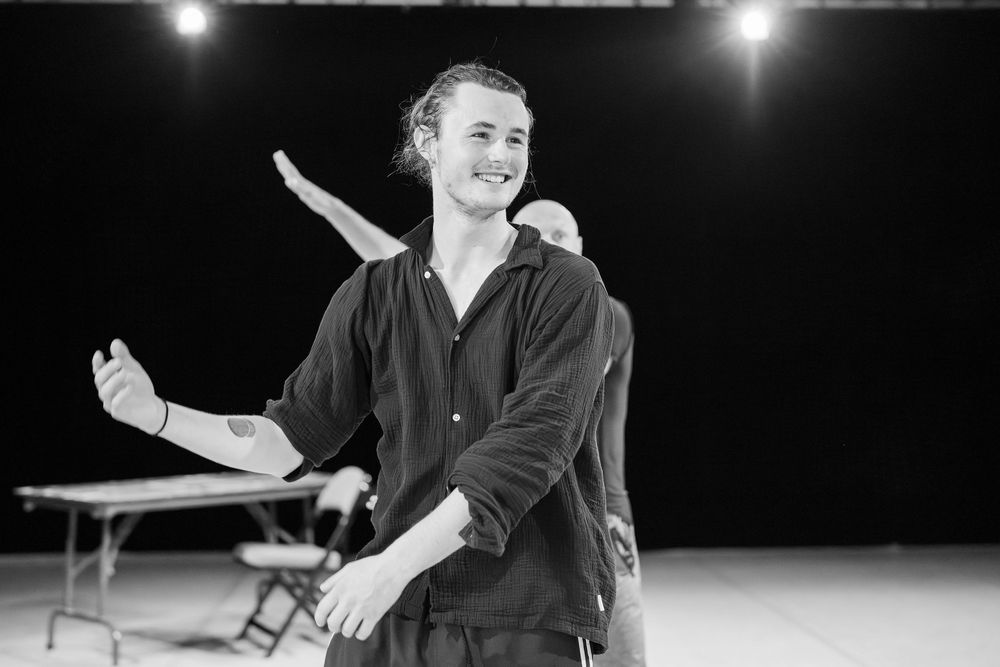 Black and white performance photos show a person in dark clothing gesturing dramatically on stage under spotlights.