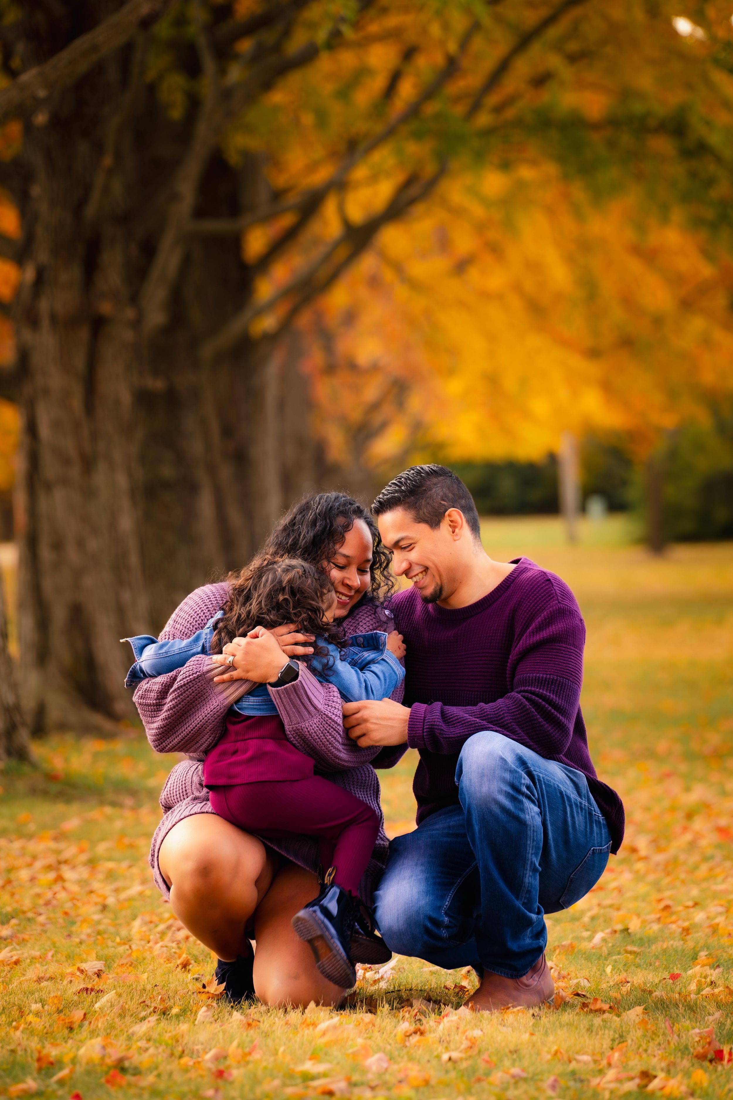 Couple sitting on autumn leaves sharing intimate moment outdoors.