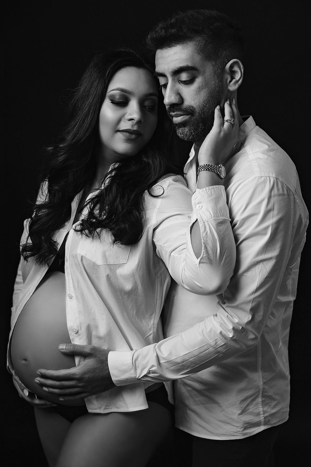 Black and white maternity portrait featuring couple in classic white dress shirt.