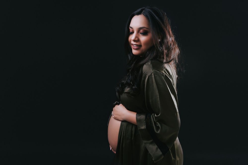 Dramatic black and white maternity portrait with moody lighting.