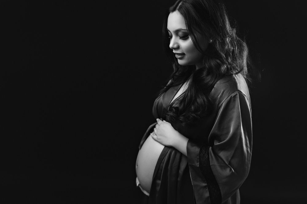 Dramatic maternity couple's portrait with moody lighting and intimate poses.