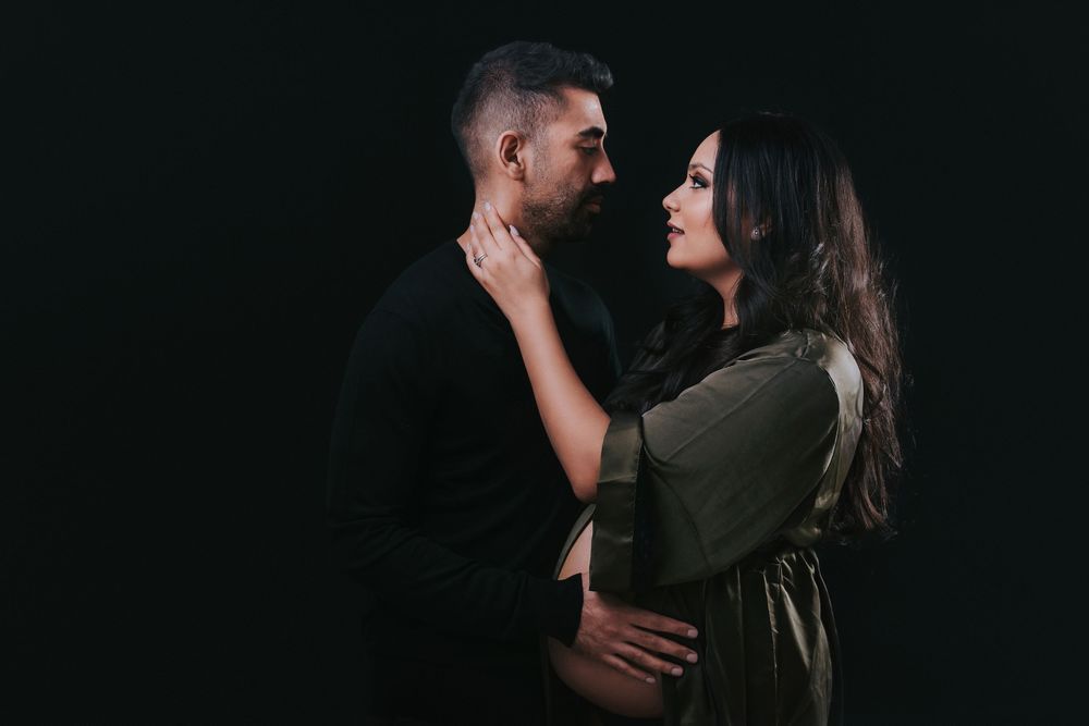 Romantic maternity couple's portrait in dramatic low-key lighting.