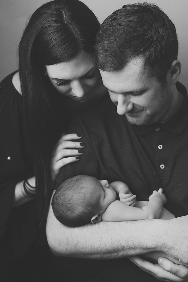 Intimate black and white portrait of parents bonding with their newborn.