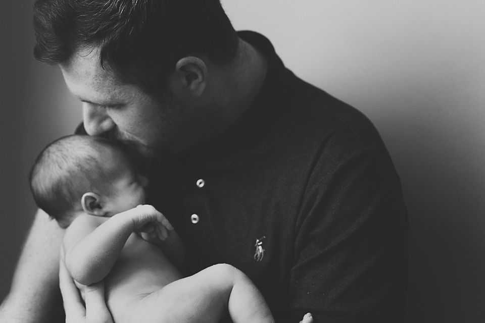 Tender moment captured in black and white as parents embrace their baby.