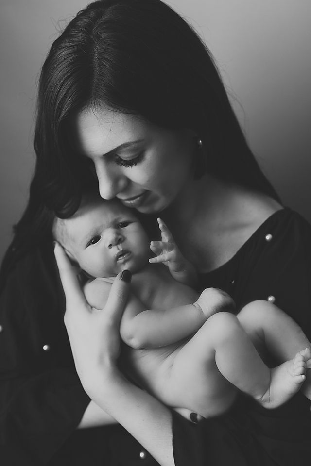 Intimate black and white portraits of mother and baby in soft lighting.
