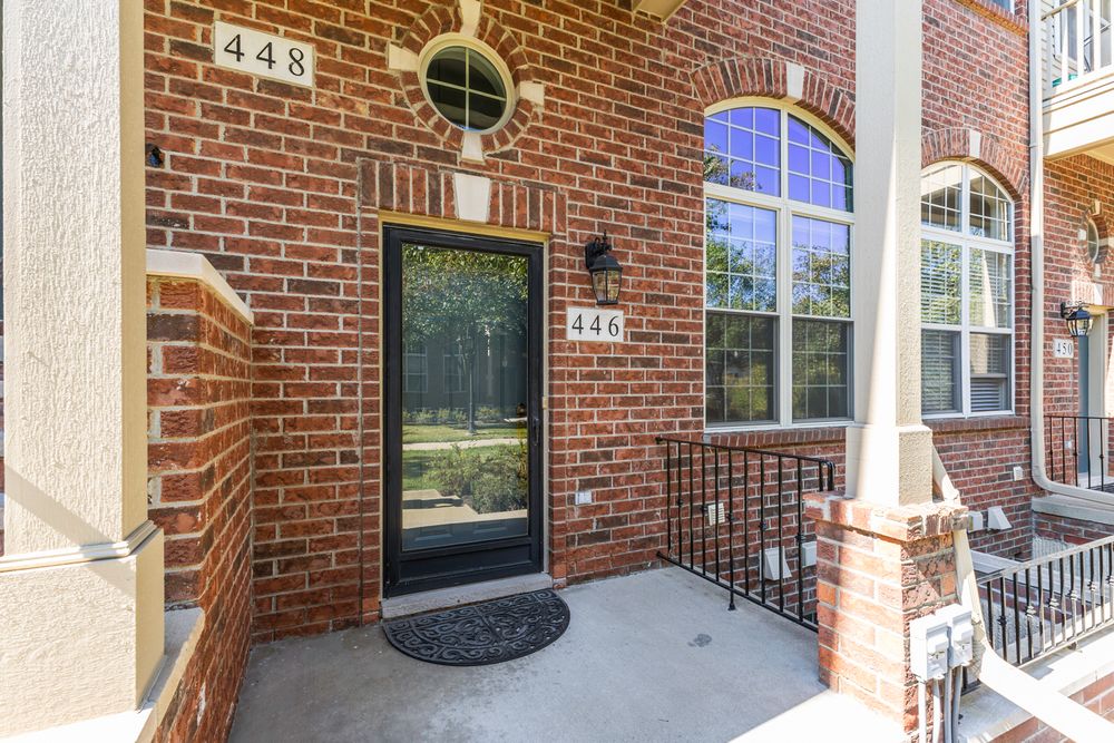 Brick townhome exterior featuring a black front door, arched window, and address numbers 448 and 446 visible.