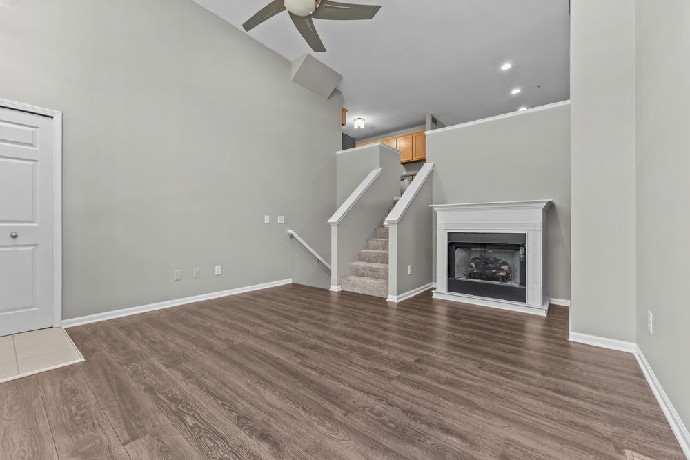 Spacious living room featuring hardwood floors, a fireplace, staircase, recessed lighting, and a ceiling fan.