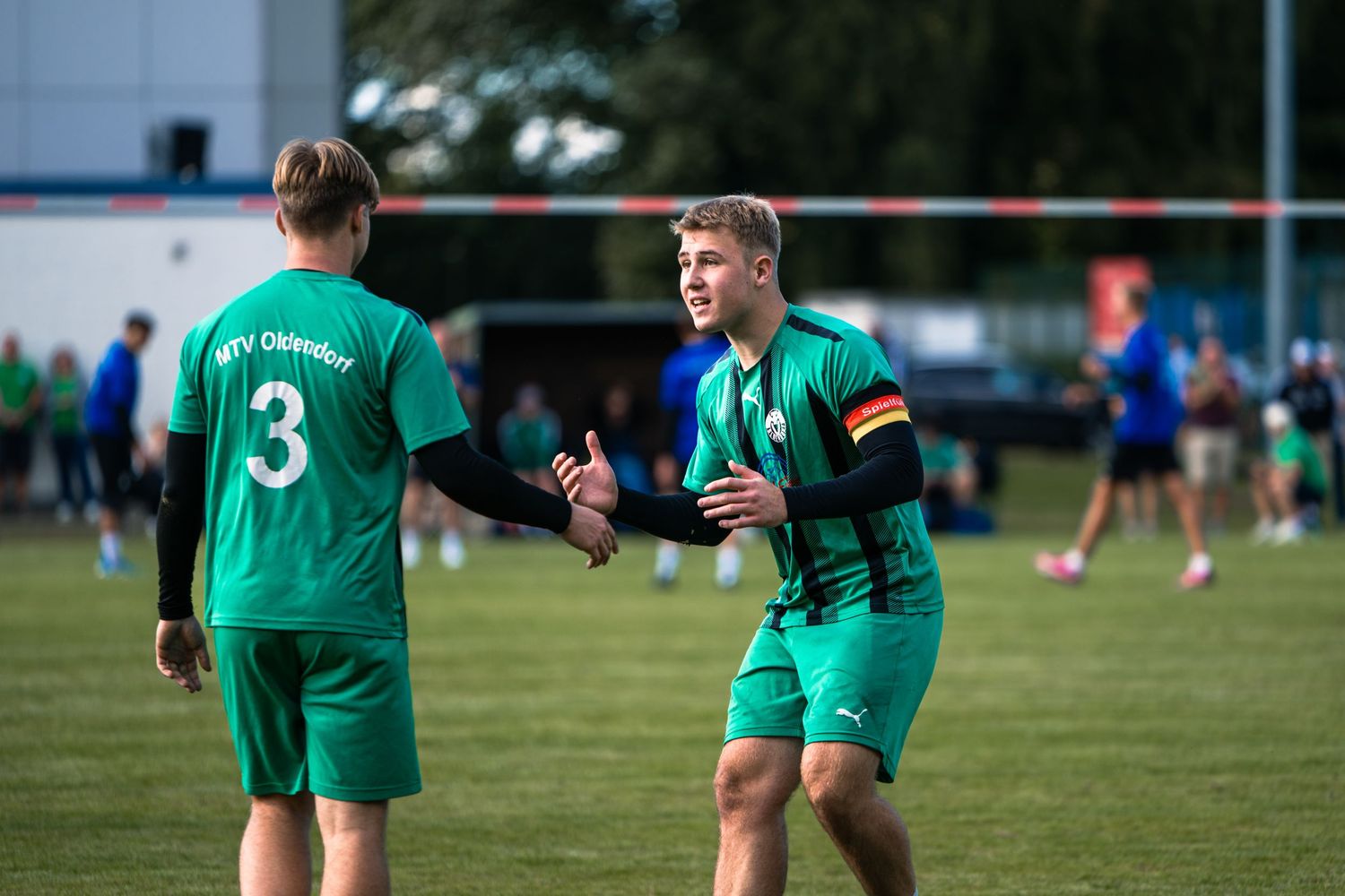 Soccer players in green jerseys compete on a grass field during a match.