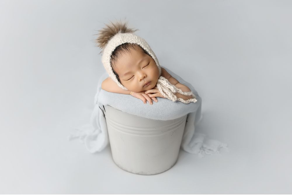 Austin newborn photographer studio portrait of sleeping baby wrapped in bucket with neutral styling