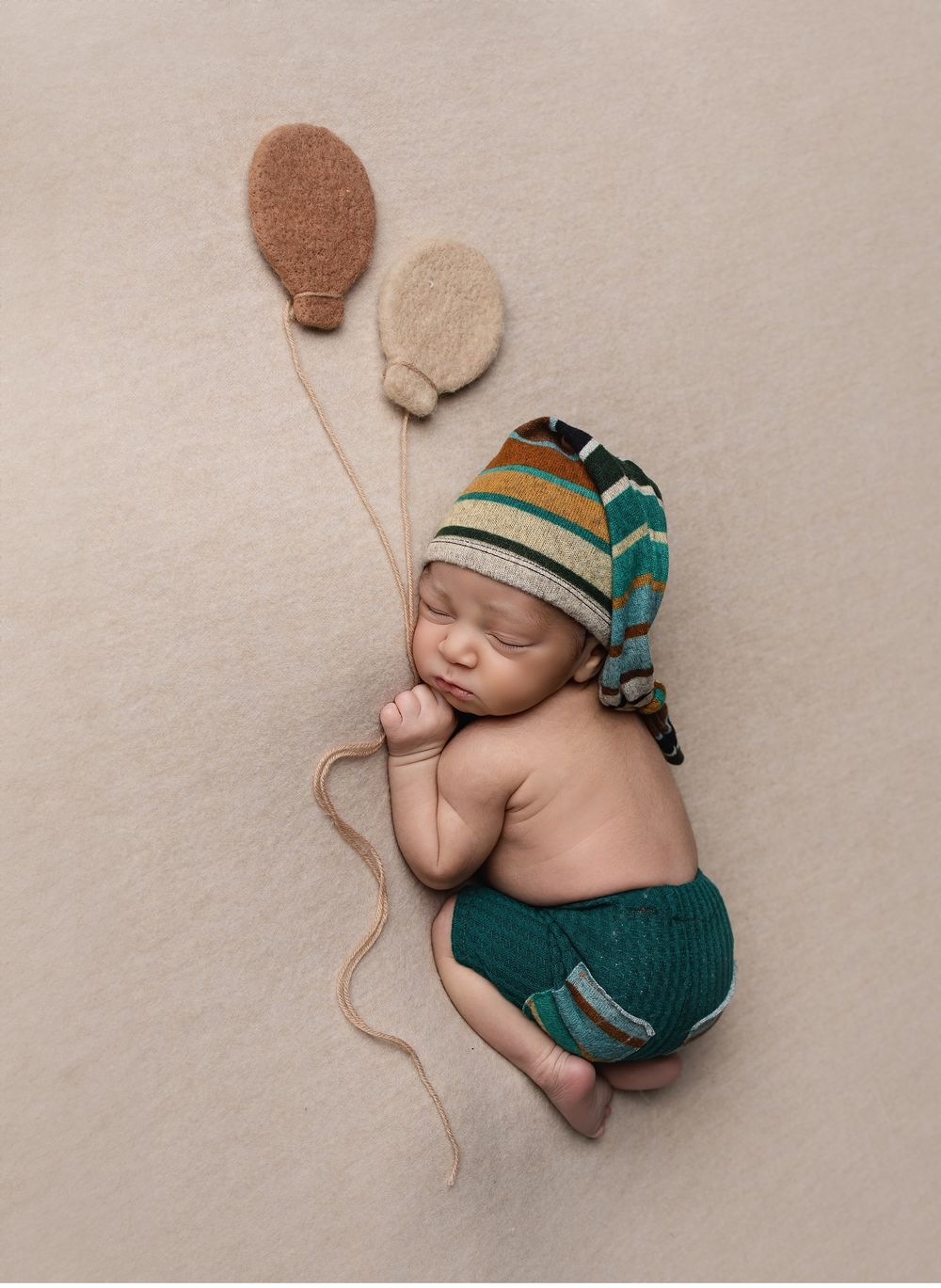 Creative newborn portrait in Austin studio featuring baby posed with balloon prop and knit bonnet