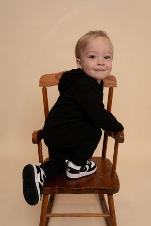 Young child playing and climbing on a wooden chair in multiple candid poses.