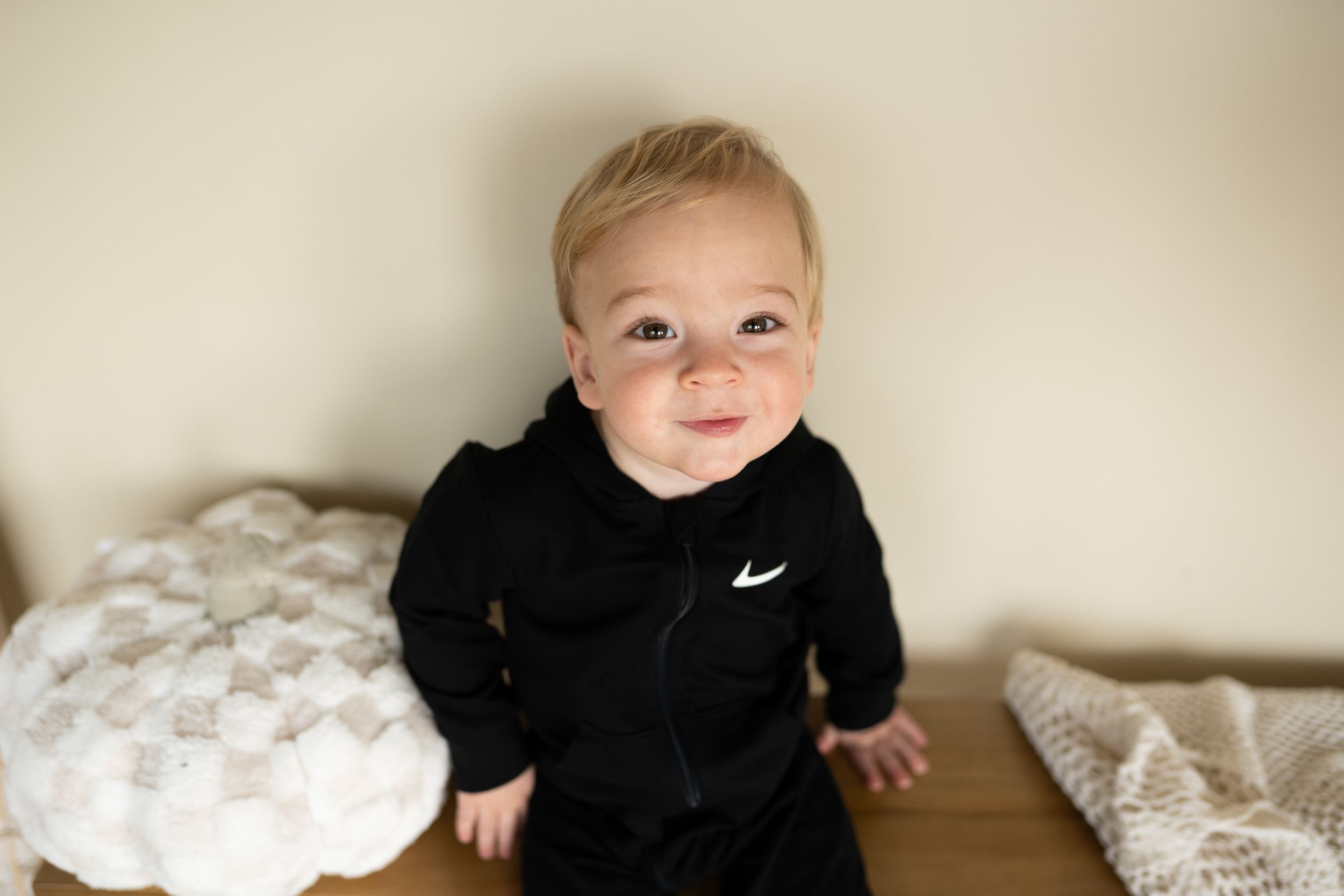 Baby in black outfit smiling and playing in studio photos.