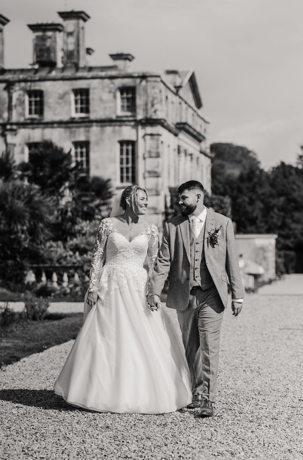 Black and white wedding photo  showing couple walking on gravel path outside elegant Kingston Mauward. Relaxed Dorset Wedding photographer