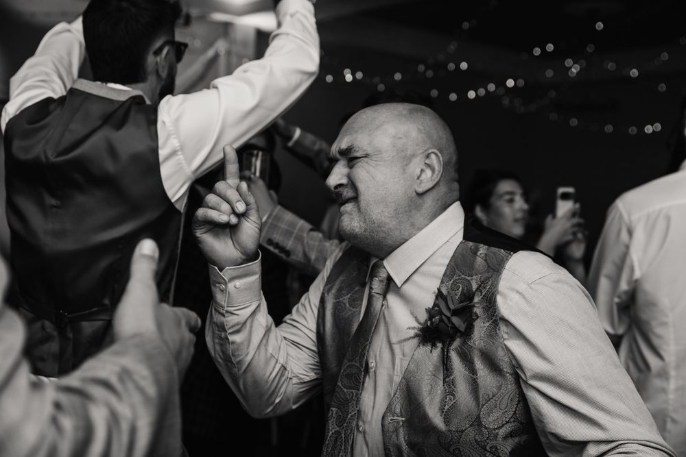 A crowd of people dancing and celebrating at a lively party with hands raised in the air. Relaxed Dorset Wedding photographer