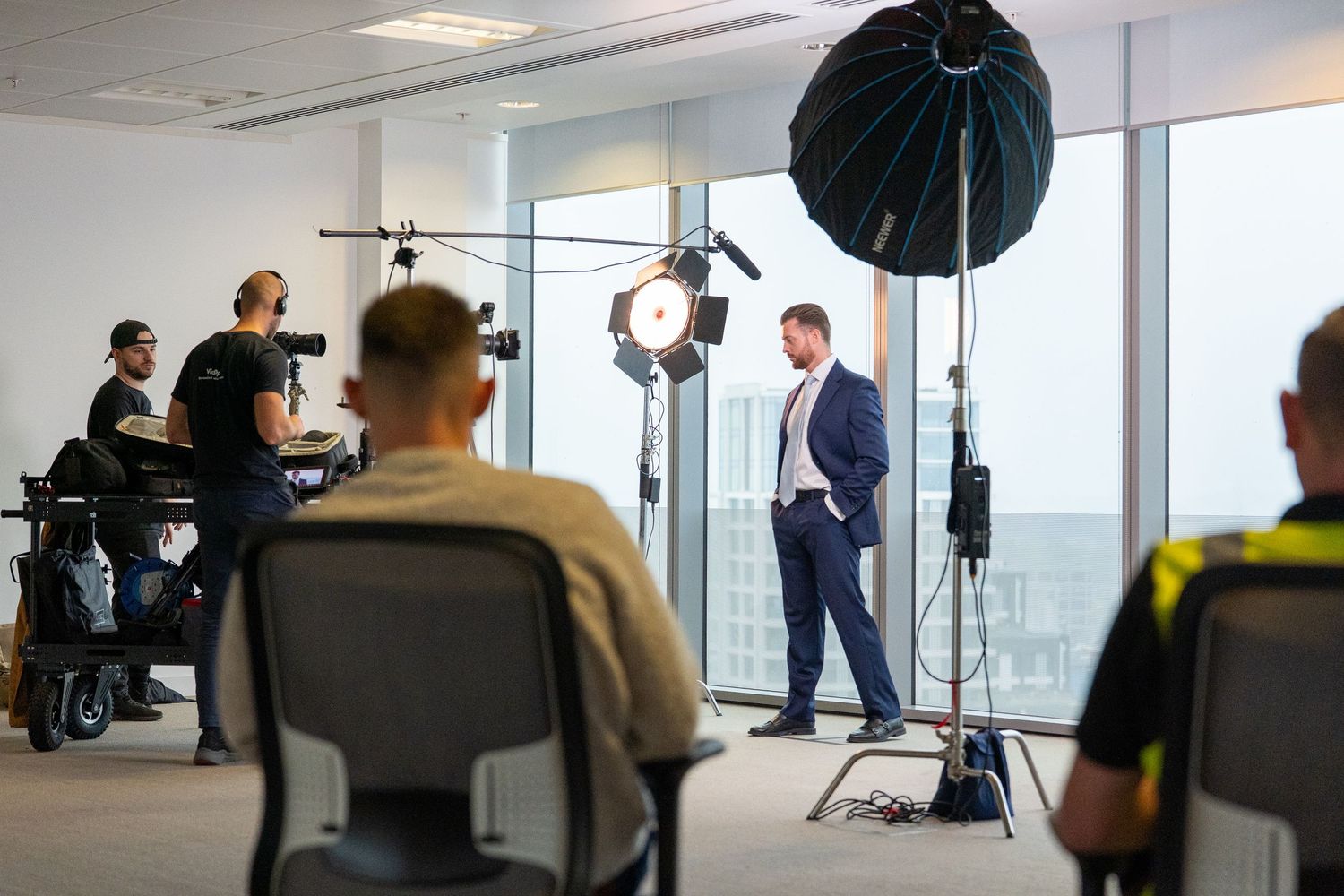 Professional photo studio setup with lighting equipment and people working in a modern office space.